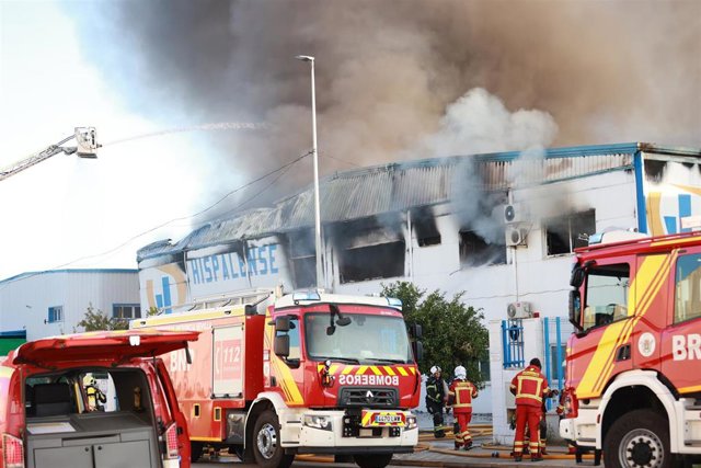 Bomberos en labores de extinción de la nave industrial en Los Espartales, en La Rinconada (Sevilla).