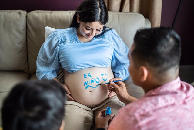 Archivo - Familia pintando el vientre embarazada de la madre en la sala de estar de casa. Embarazo