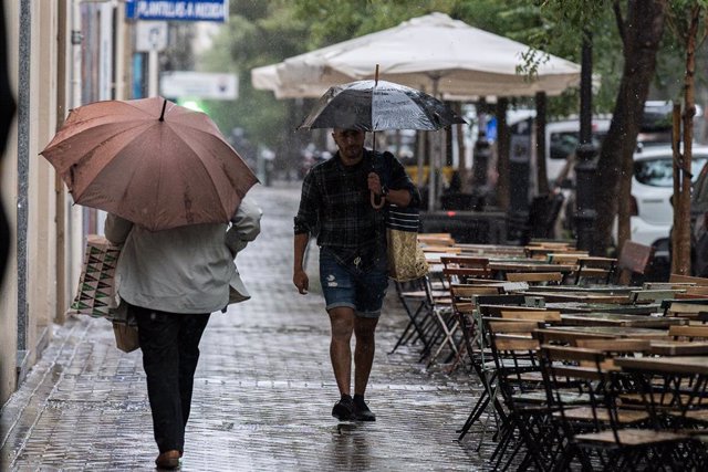 Varias personas se resguardan de la lluvia con paraguas, archivo