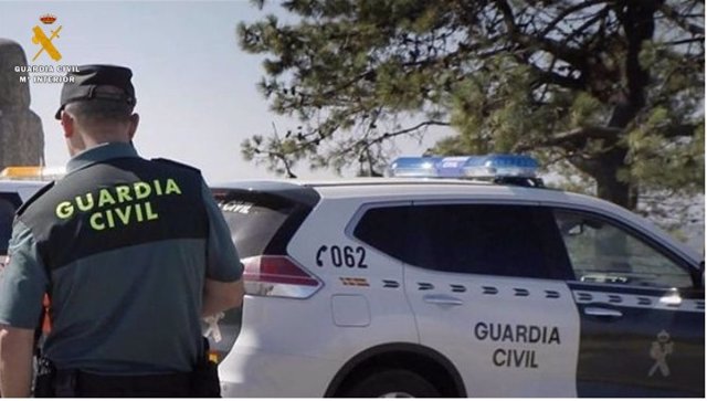 Agente de la Guardia Civil ante un coche patrulla, en imagen de archivo