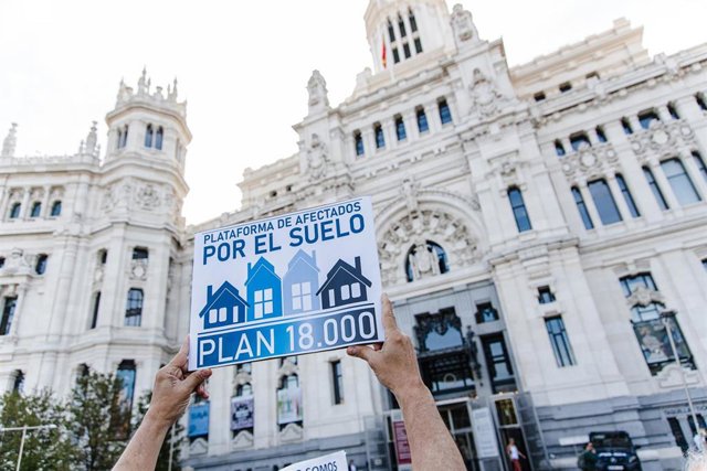 Archivo - Una persona sujeta una pancarta durante una protesta sobre el Plan 18000 Venta de Suelo frente a las puertas del Ayuntamiento de Madrid