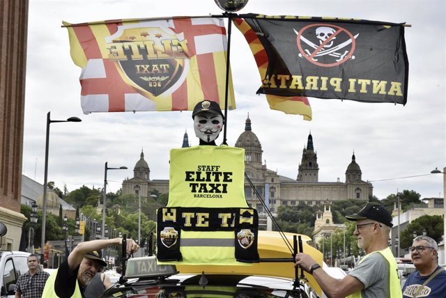 Archivo - Pancartas y banderas de Élite Taxi durante una marcha lenta en Barcelona.
