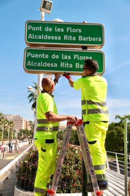Operarios del Ayuntamiento de València instalan el cartel del 'Puente de las Flores-Rita Barberá'