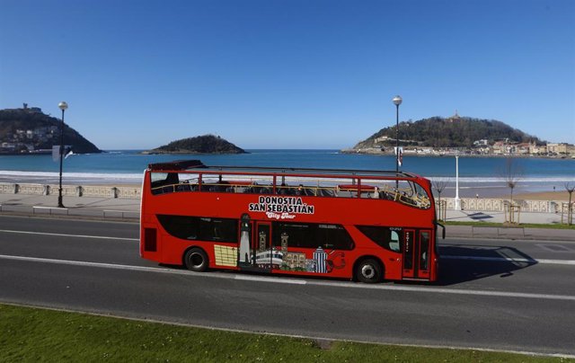 Archivo - Un autobús turístico en una carretera junto a la Playa de la Concha en San Sebastián