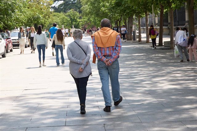 Archivo - Una pareja camina por Paseo del Prado.