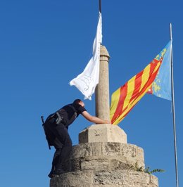 La Policía Local de Valencia retira una bandera con versículos del Corán que se ha colocado en las Torres de Serranos junto a un ejemplar de este libro.