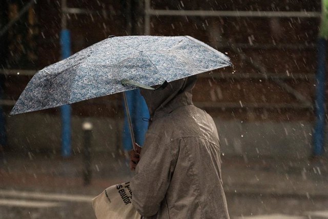 Archivo - Una dona amb paraigua sota la pluja