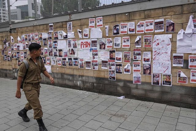 Militar israelí pasea delante de carteles de desaparecidos y secuestrados 