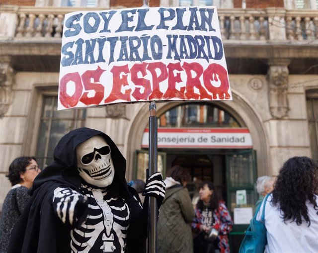 Archivo - Una persona vestida con un disfraz de esqueleto sujeta una pancarta en protesta por el plan sanitario madrileño, en una imagen de archivo