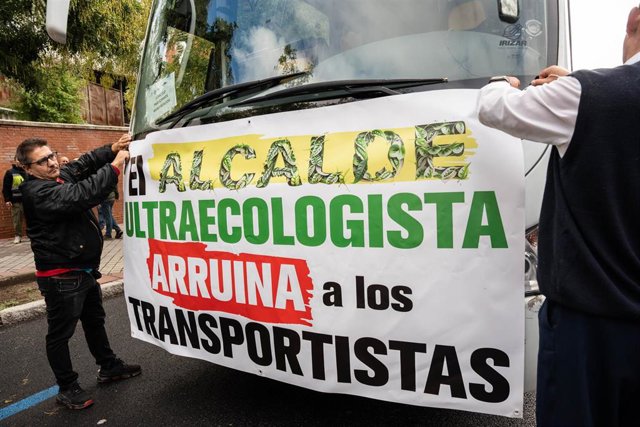 Dos transportistas ponen una pancarta en un camión durante una marcha lenta de transportistas en protesta por las prohibiciones de acceso a vehículos profesionales a Zona de Bajas Emisiones, a 30 de octubre de 2023, en Madrid (España). 
