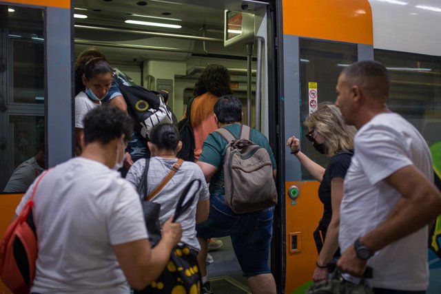 Archivo - Viatgers pugen a un tren de Rodalies.