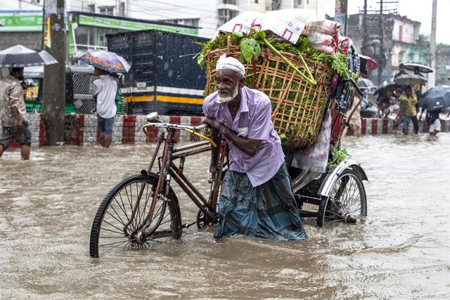 Archivo - 05 August 2023, Bangladesh, Chittagong: A man wades through flood waters and heavy rain in Chittagong. Photo: Muhammad Amdad Hossain/ZUMA Press Wire/dpa