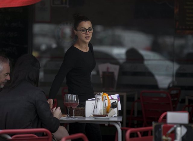 Archivo - Una camarera atiende la mesa de un bar en Sevilla. Imagen de archivo.