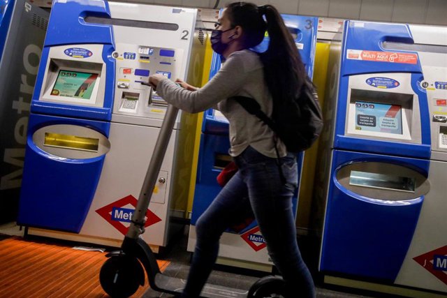Archivo - Una mujer entra con un patinete eléctrico en el metro 