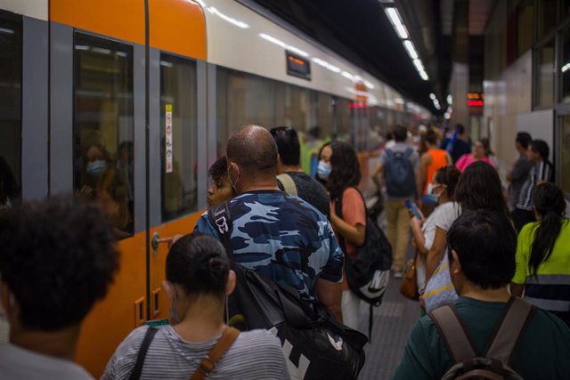 Archivo - Viajeros suben a un tren en uno de los andenes de la estación de Sants