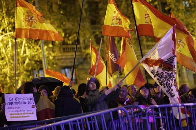 Decenas de personas portan banderas y carteles detrás de las vallas puestas por la Policía, durante una protesta en la calle Ferraz, a 10 de noviembre de 2023, en Madrid (España). 