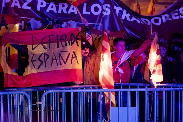 Varias personas queman una bandera estelada durante una manifestación contra la amnistía frente a la sede del PSOE en Ferraz, a 15 de noviembre