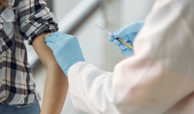 Imagen de recurso de un profesional sanitario administrando la vacuna frente a la meningitis a un joven.