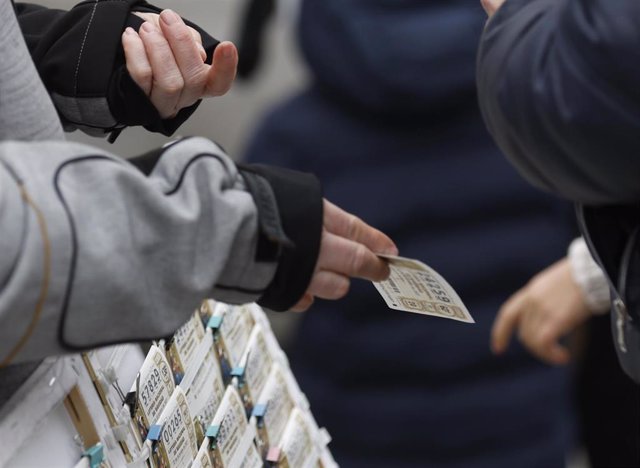 Archivo - Una personas compra un décimo de lotería de Navidad a una vendedora ambulante cuando quedan menos de tres semanas para el Sorteo Extraordinario de la Lotería de Navidad, a 7 de diciembre de 2021, en Madrid (España). Como cada año, la Lotería de 