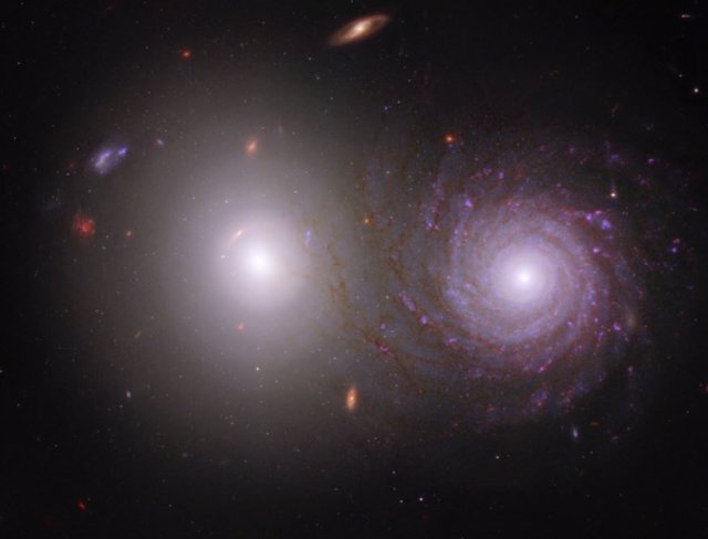 Esta imagen, que muestra una galaxia elíptica (izquierda) y una galaxia espiral (derecha), incluye luz infrarroja cercana del Telescopio Espacial James Webb y luz ultravioleta y visible del Telescopio Espacial Hubble.