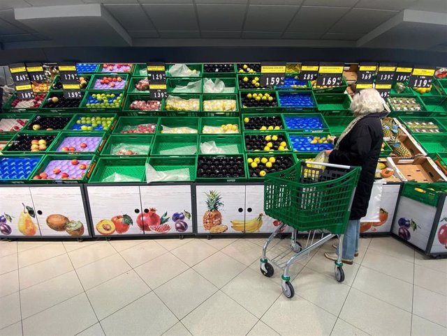 Archivo - Un mujer coloca fruta en una bolsa 