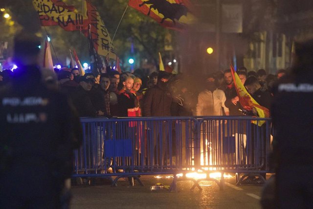Varias personas queman una bandera estelada, durante la protesta en la calle Ferraz de Madrid 