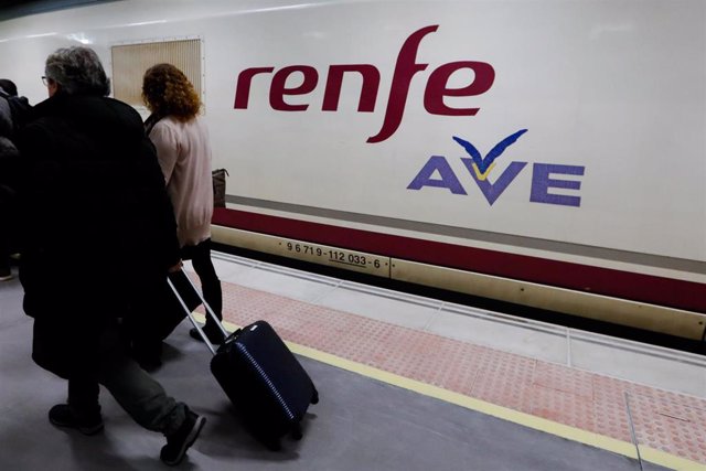 Archivo - Dos pasajeros pasan por delante del primer tren comercial de alta velocidad desde Murcia a Madridaño.
