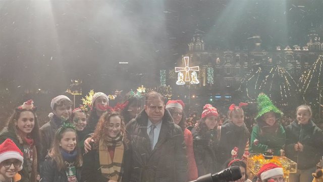 El alcalde de Oviedo, Alfredo Canteli, en el escenario instalado en la calle Uría para el encendido navideño, acompañado de miembros del coro Arsis.
