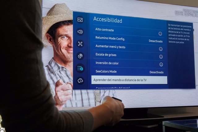 Una persona muestra ayudas a la accesibilidad en un modelo de televisión durante un encuentro con personas con discapacidad visual y auditiva, a 1 de diciembre de 2023, en Madrid (España).