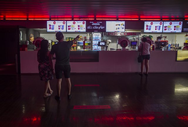 Dos personas eligen un menú de palomitas y refresco en el primer fin de semana con estrenos en las salas de cine tras la supresión del Estado de Alarma. En Nervión Plaza, (Sevilla, Andalucía, España), a 26 de junio de 2020.