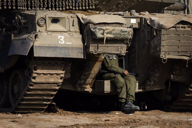Un militar israelí sentado junto a vehículos cerca de la frontera de la Franja de Gaza