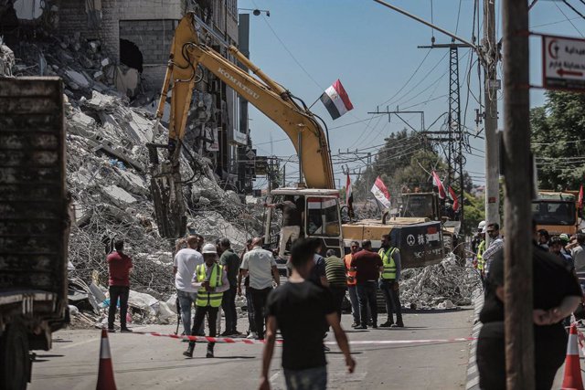 Archivo - 05 June 2021, Palestinian Territories, Gaza City: Palestinians watch an excavator run by an Egyptian team clearing up the rubble of Al-Shorouk Tower that was hit and destroyed during the recent Israeli airstrikes. 