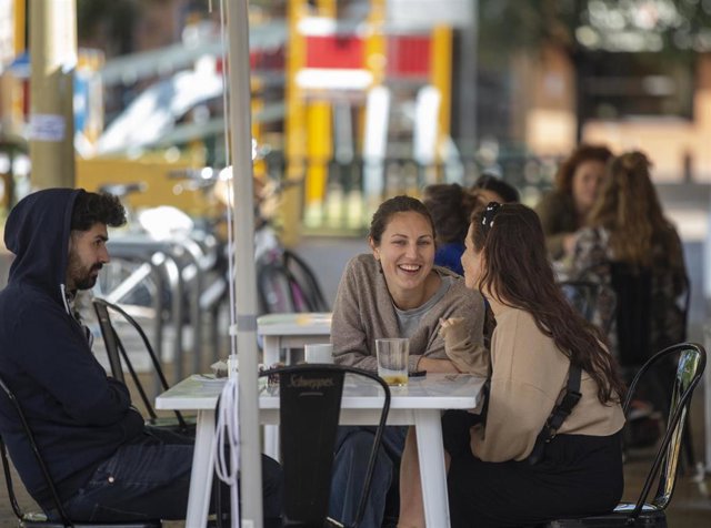 Archivo - Un grupo de personas sentadas en los veladores de un bar en Sevilla, foto de archivo