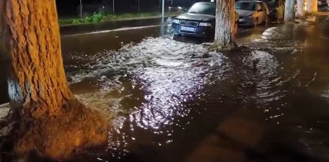 Agua saliendo en la calle Betis, en Lora del Río, tras reventar la tubería que la atraviesa.