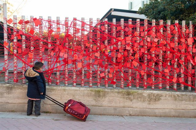 Archivo - Un niño observa un muro lleno de papeles de deseos en Madrid.