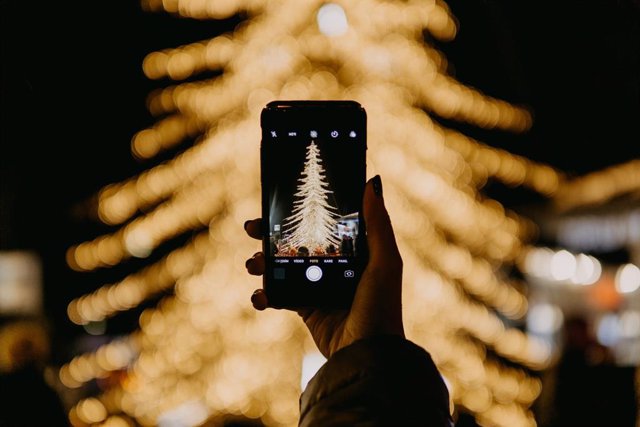 Persona fotografiando árbol de navidad.