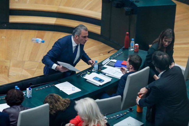 Momento en el que el portavoz de Vox en el Ayuntamiento de Madrid, Javier Ortega Smith, se encara y tira unos papeles y una botella de agua vacía al edil Eduardo Fernández Rubiño, concejal de Más Madrid, en su escaño.