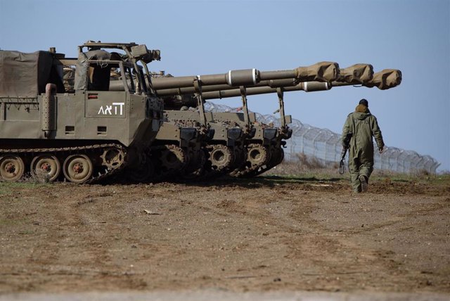 Archivo - Un soldado israelí pasa junto a obuses autopropulsados M109 de 155 mm en los Altos del Golán ocupados por Israel, cerca de la frontera con Siria