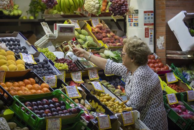 Archivo - Una mujer compra en uno de los puestos del mercado de abastos de Triana, en Sevilla. Imagen de archivo.