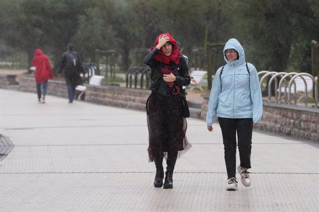 Archivo - Dos personas caminan bajo la lluvia en la playa de Ondarreta, a 14 de octubre de 2023, en San Sebastián, Guipúzcoa, País Vasco (España). 