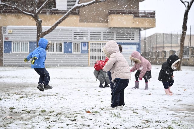 Varios niños juegan en la calle bajo la nieve, a 19 de enero de 2024, en Zaragoza.