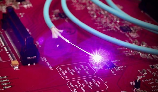 Luz que viaja a través de una fibra óptica situada encima de una placa de circuito electrónico convencional.
