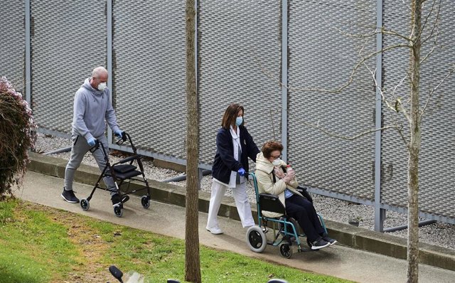 Archivo - Una profesional sanitaria pasea con pacientes del Hospital Universitario Marqués de Valdecilla