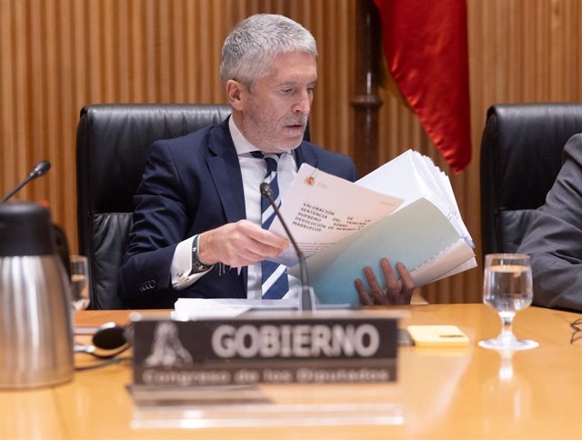 El ministro de Interior, Fernando Grande-Marlaska, con uno de los documentos de la sentencia de la devolución de menores desde Ceuta a Marruecos, ordenada por él en 2021, durante la Comisión de Interior, en el Congreso de los Diputados.