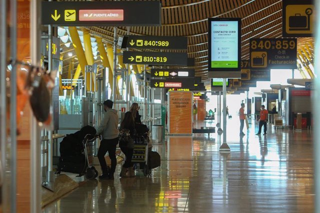 Archivo - Tres personas caminan con su equipaje en la Terminal T4 del Aeropuerto Adolfo Suárez Madrid-Barajas