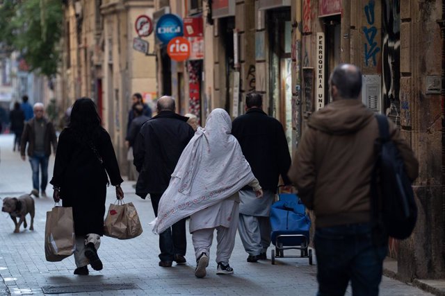 Diverses persones caminen carregades per un carrer, a 24 de gener del 2024, a Barcelona