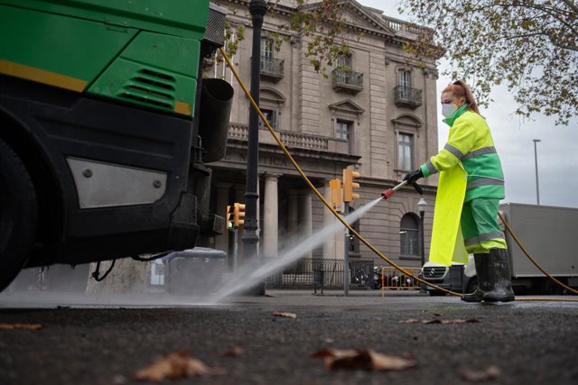 Una treballadora rega un carrer amb una mànega al gener