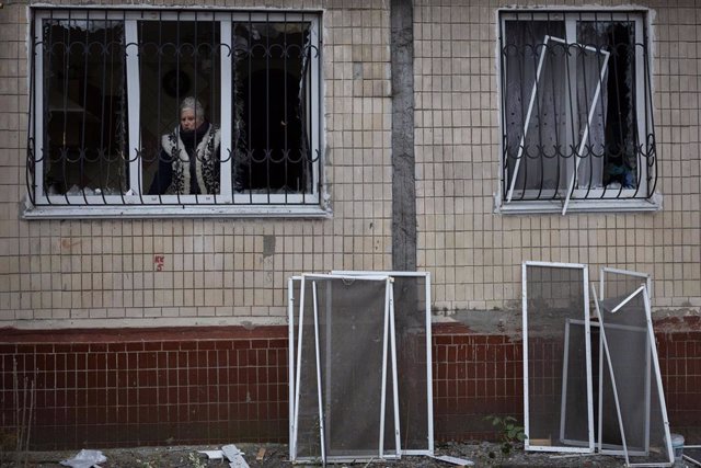 Archivo - Una mujer mira por la ventana de un edificio dañado a causa de un ataque del Ejército de Rusia contra la capital de Ucrania, Kiev (archivo)
