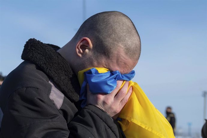 Archivo - Un prisionero de guerra ucranano llora en la bandera de su país tras ser liberado de cautiverio ruso
