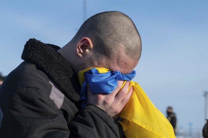 Archivo - Un prisionero de guerra ucranano llora en la bandera de su país tras ser liberado de cautiverio ruso